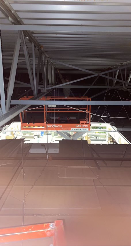 Worker on a scissor lift welding structural steel trusses
